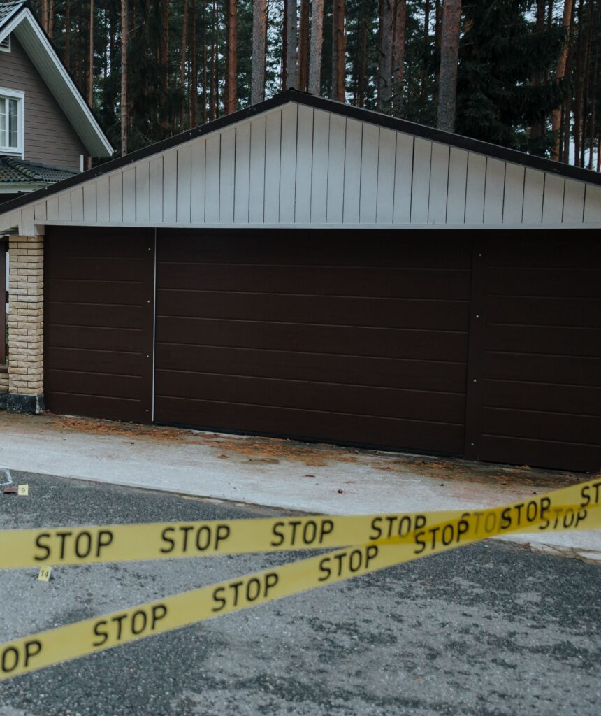A residential garage cordoned off with yellow STOP tape, representing the professional site management required for AllAces trauma cleaning services.