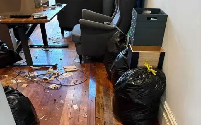 Professional estate and home clear out showing a cluttered floor with scattered debris and full trash bags.