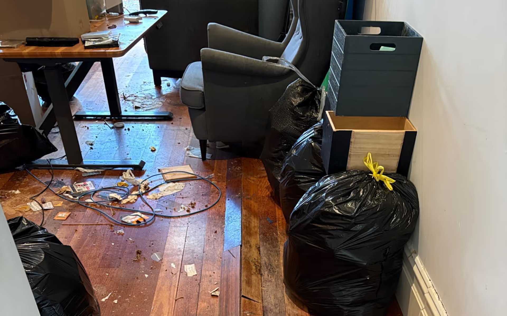 Professional estate and home clear out showing a cluttered floor with scattered debris and full trash bags.