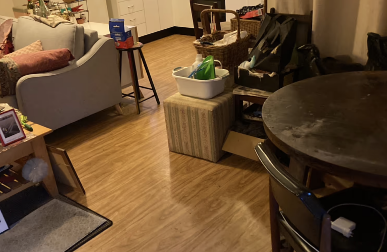 Messy living room filled with clutter, scattered belongings, and outdated furniture, creating a dull and disorganised space before estate and home clear out