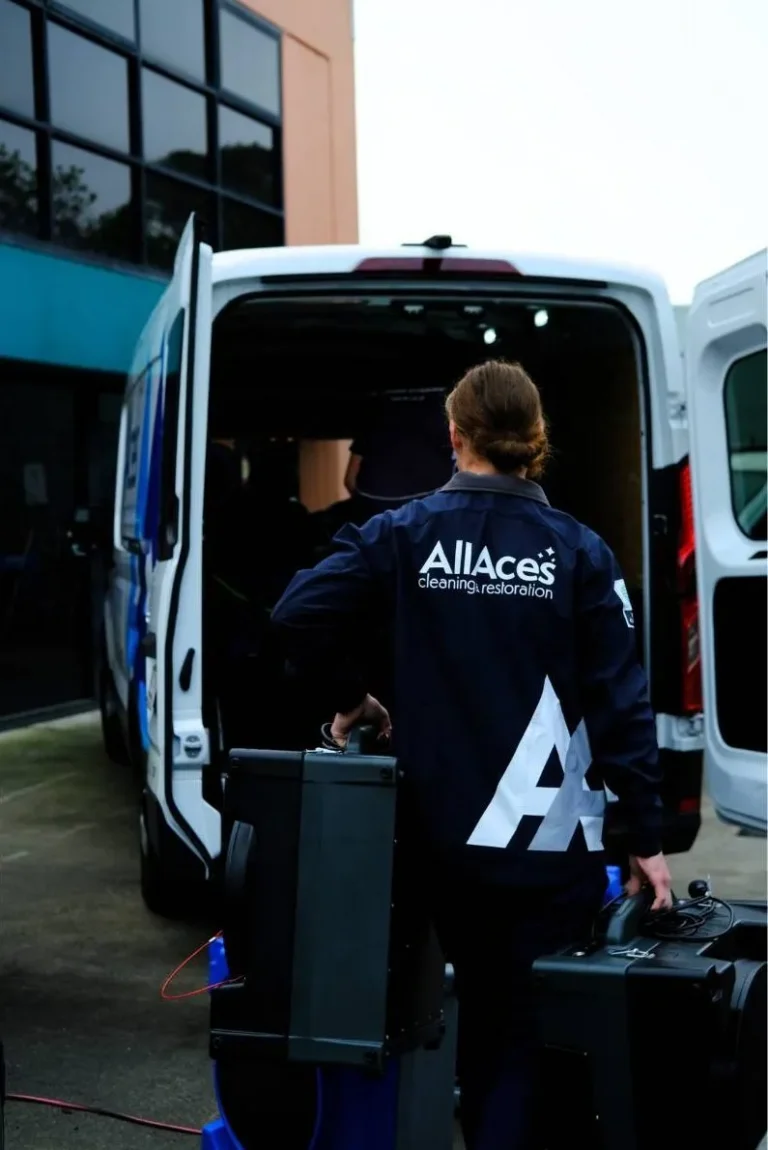 A technician from AllAces Cleaning & Restoration loading professional equipment into a service van, showcasing expert restoration readiness.