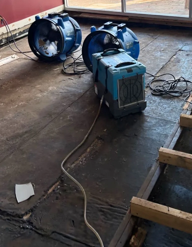 Commercial structural drying fans and dehumidifier equipment set up on a subfloor during a water damage restoration Ballarat project.